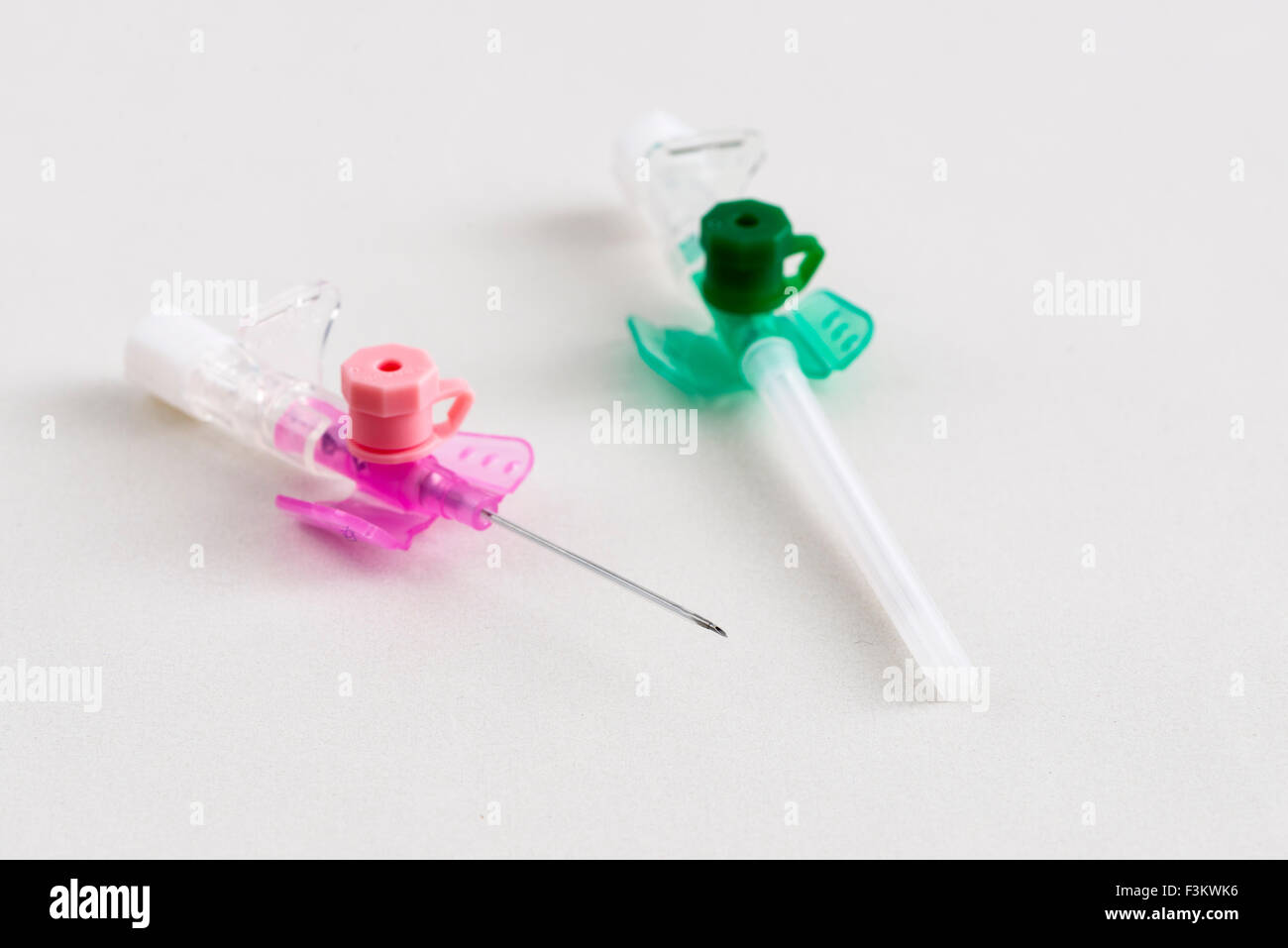 Una rosa una sicurezza verde catetere iv con porta di iniezione per uso medico, visualizzato su un tavolo bianco Foto Stock