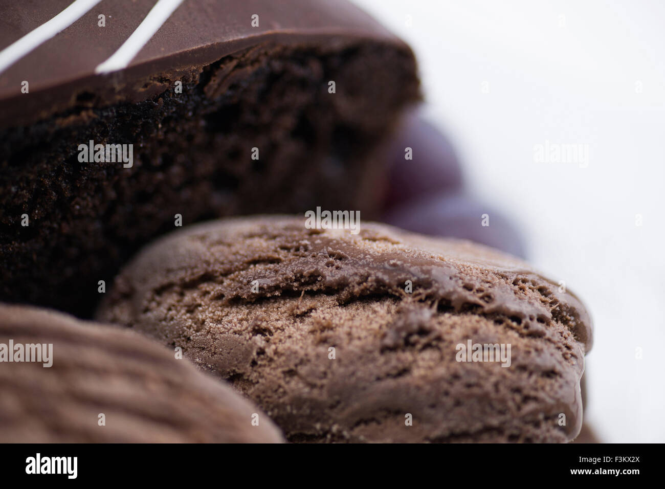 Macro di ricca torta al cioccolato, fresco gelato al cioccolato e uva in bokeh di fondo contro uno sfondo bianco Foto Stock