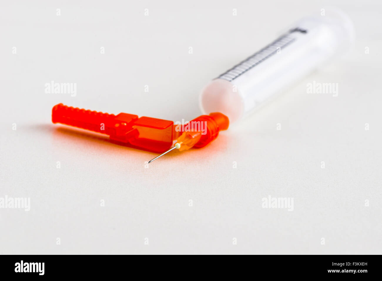 Una siringa con un ago ipodermico per uso medico, visualizzato su un tavolo bianco Foto Stock