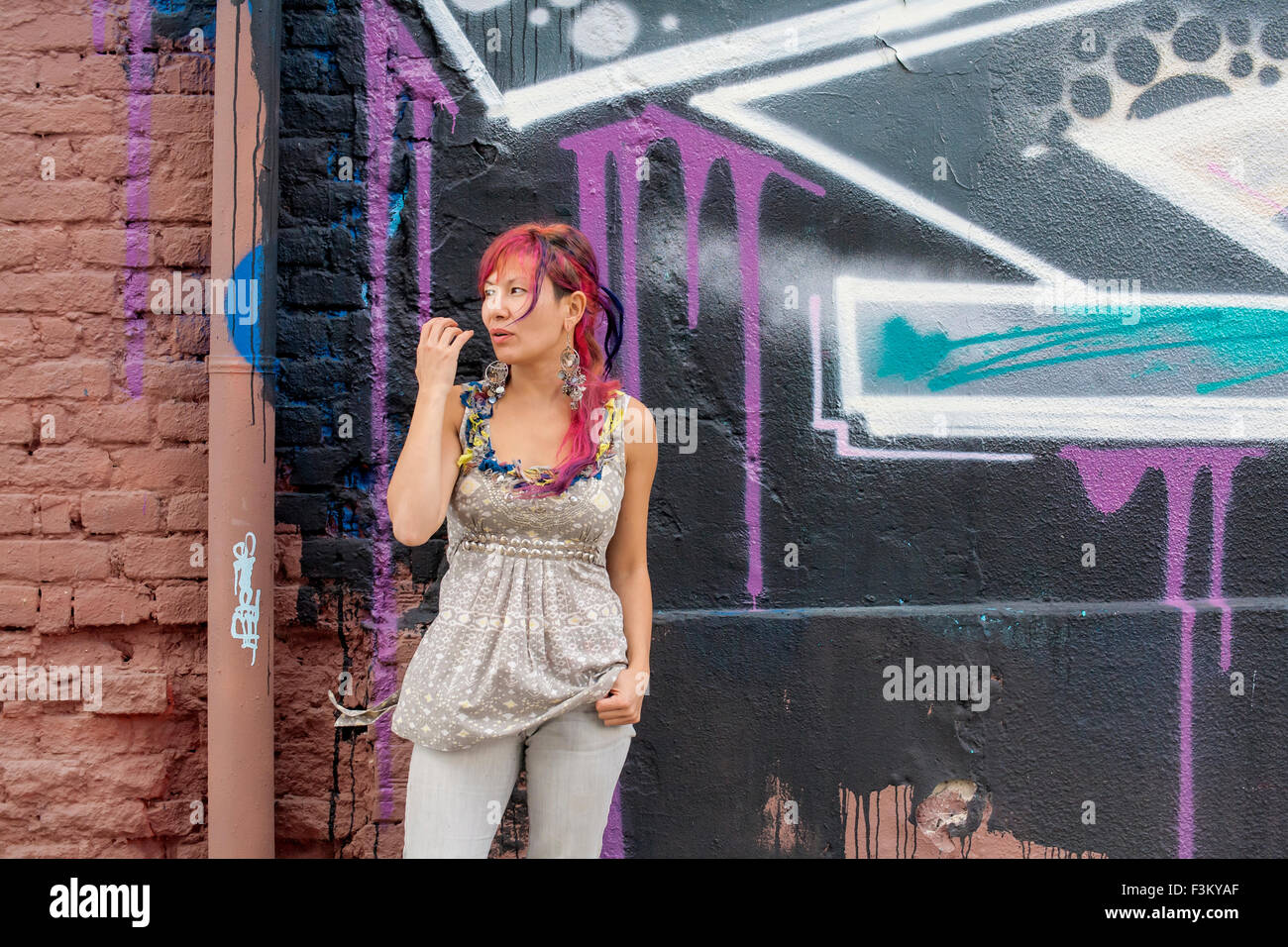 Giovane bella ragazza in harajuku stile con capelli colorati e freaky outfit davanti al muro con la street art pittura Foto Stock