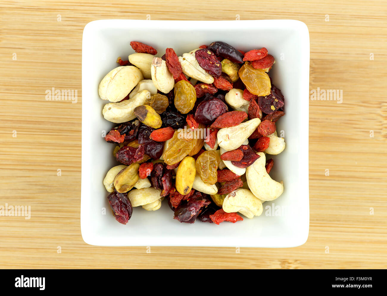 Miscugli di frutta e noci in ciotola bianco su sfondo di legno Foto Stock