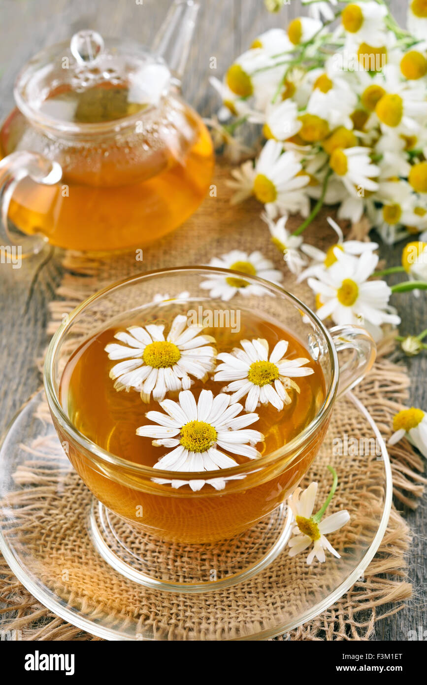 La camomilla tè in tazza di vetro, teiera e fiori sul tavolo di legno Foto  stock - Alamy