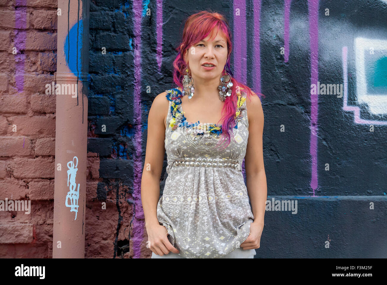 Giovane bella ragazza in harajuku stile con capelli colorati e freaky outfit davanti al muro con la street art pittura Foto Stock