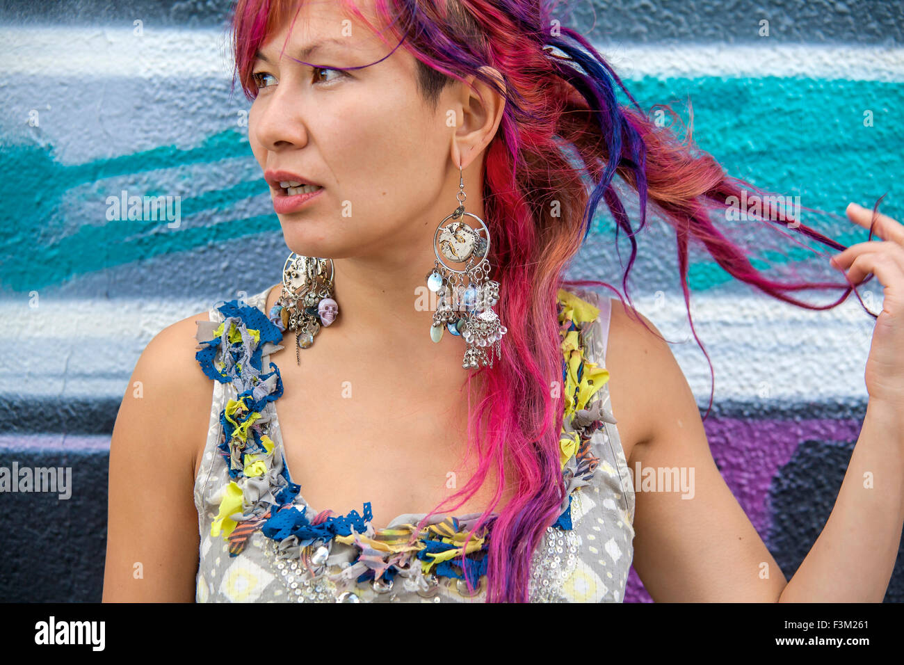 Giovane bella ragazza in harajuku stile con capelli colorati e freaky outfit davanti al muro con la street art pittura Foto Stock