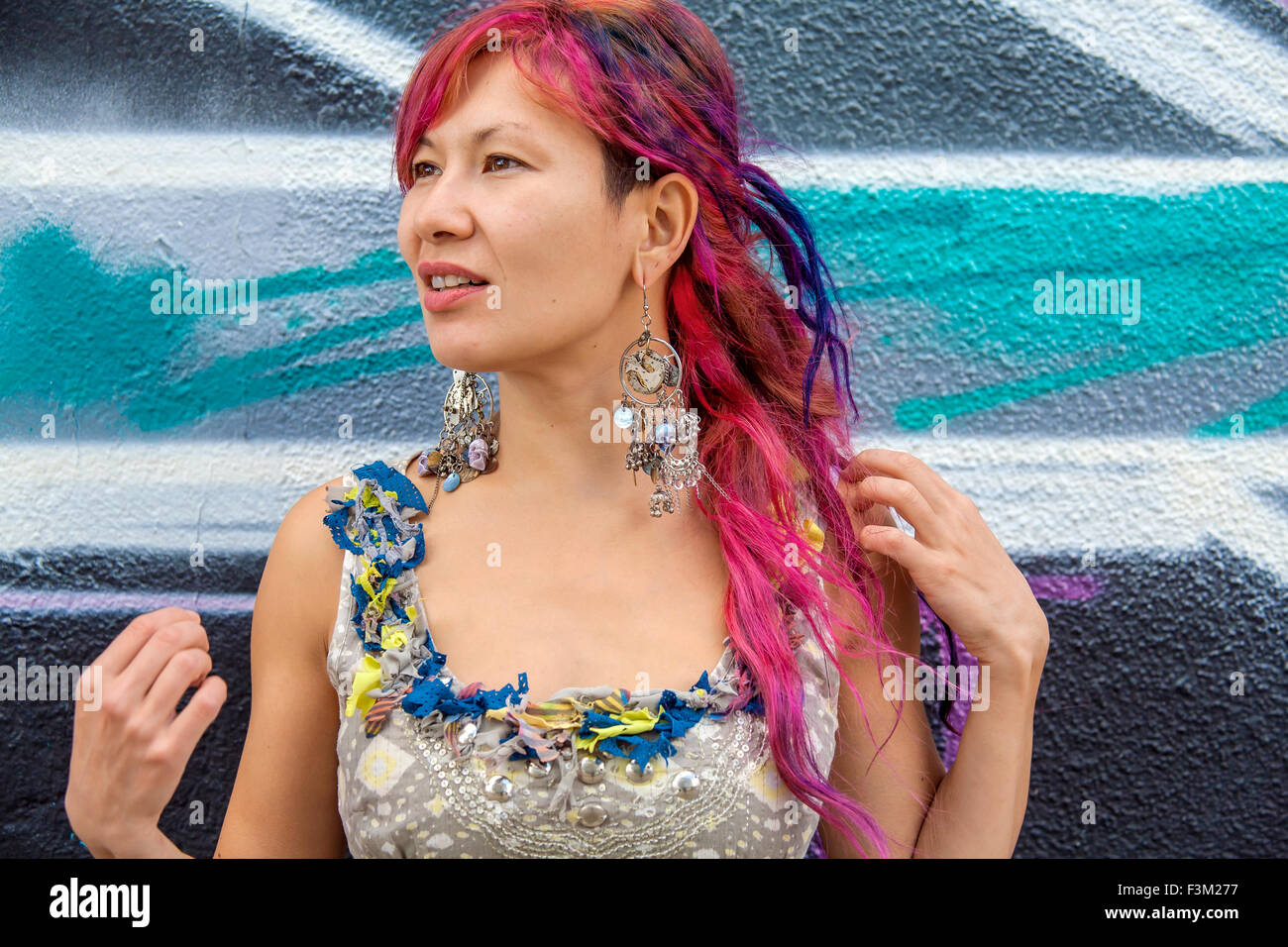 Giovane bella ragazza in harajuku stile con capelli colorati e freaky outfit davanti al muro con la street art pittura Foto Stock