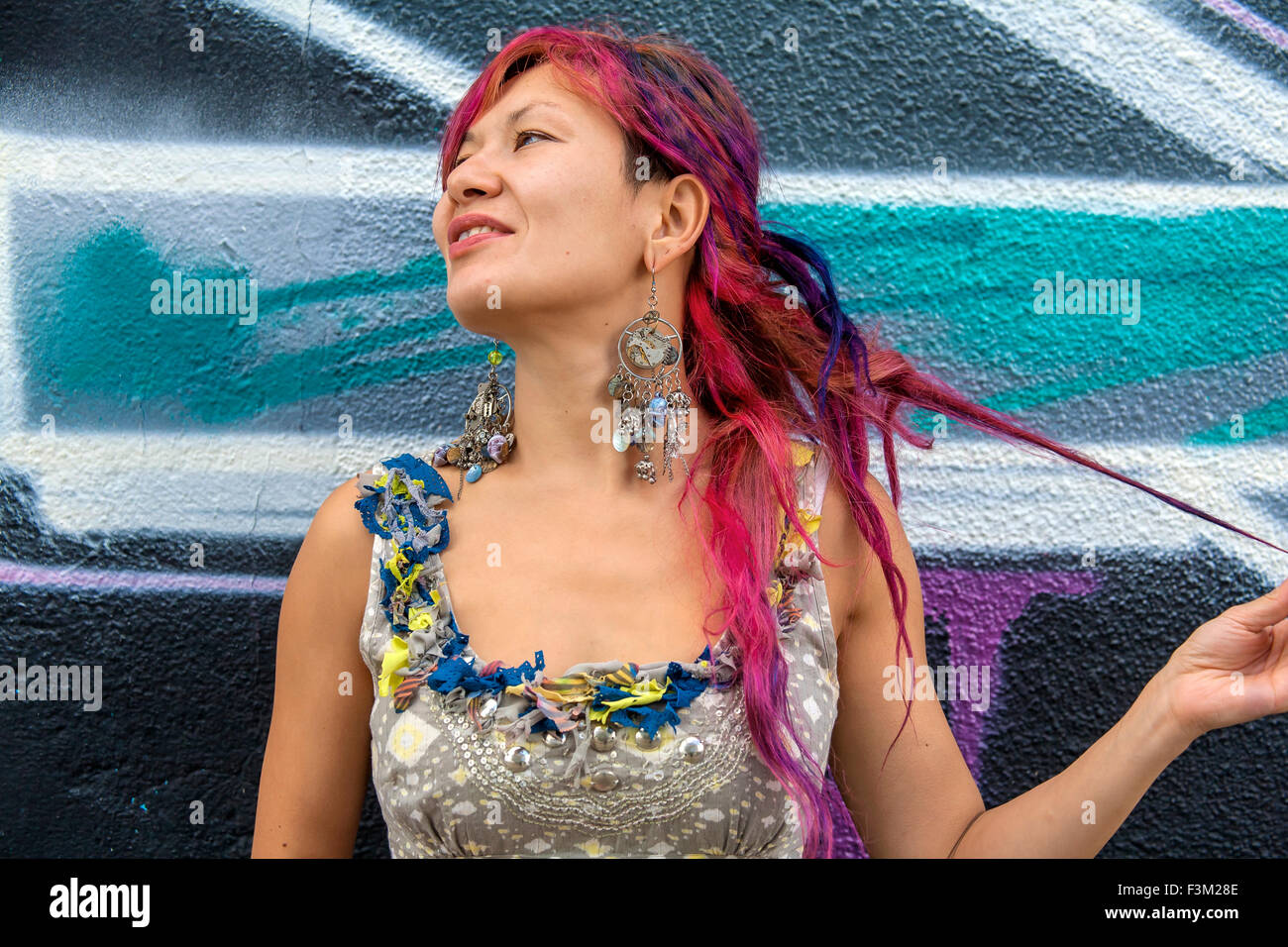 Giovane bella ragazza in harajuku stile con capelli colorati e freaky outfit davanti al muro con la street art pittura Foto Stock