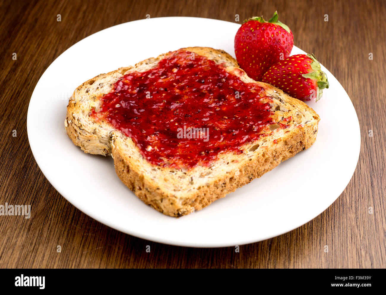 Confettura di fragole spalmato su multi-granella pane tostato Foto Stock Confettura di fragole spalmato su multi-granella pane tostato Foto Stock