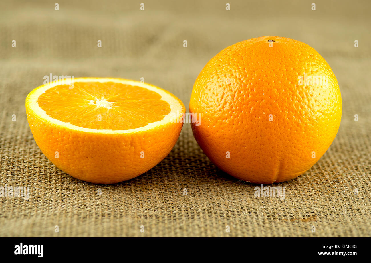 Perfetto arancione con sezione trasversale contro la tela rustico sfondo di Hesse Foto Stock