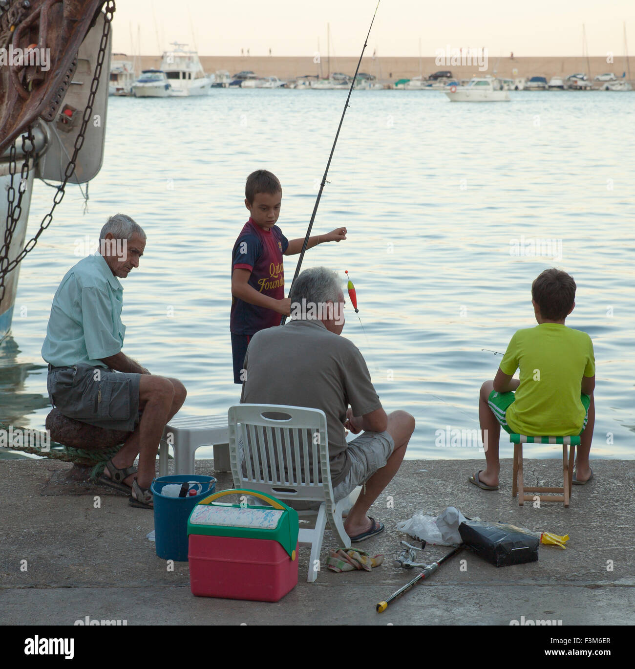 Gli uomini e i ragazzi con attività di pesca in un porto spagnolo. Foto Stock
