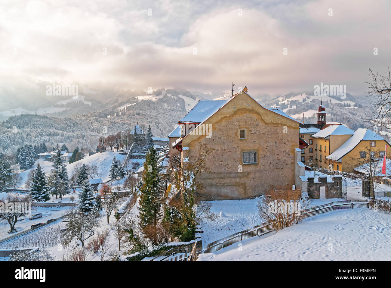 Inverno a Gruyeres, Svizzera. Coperte di neve paesaggio di montagna con vecchie case di pietra in primo piano Foto Stock