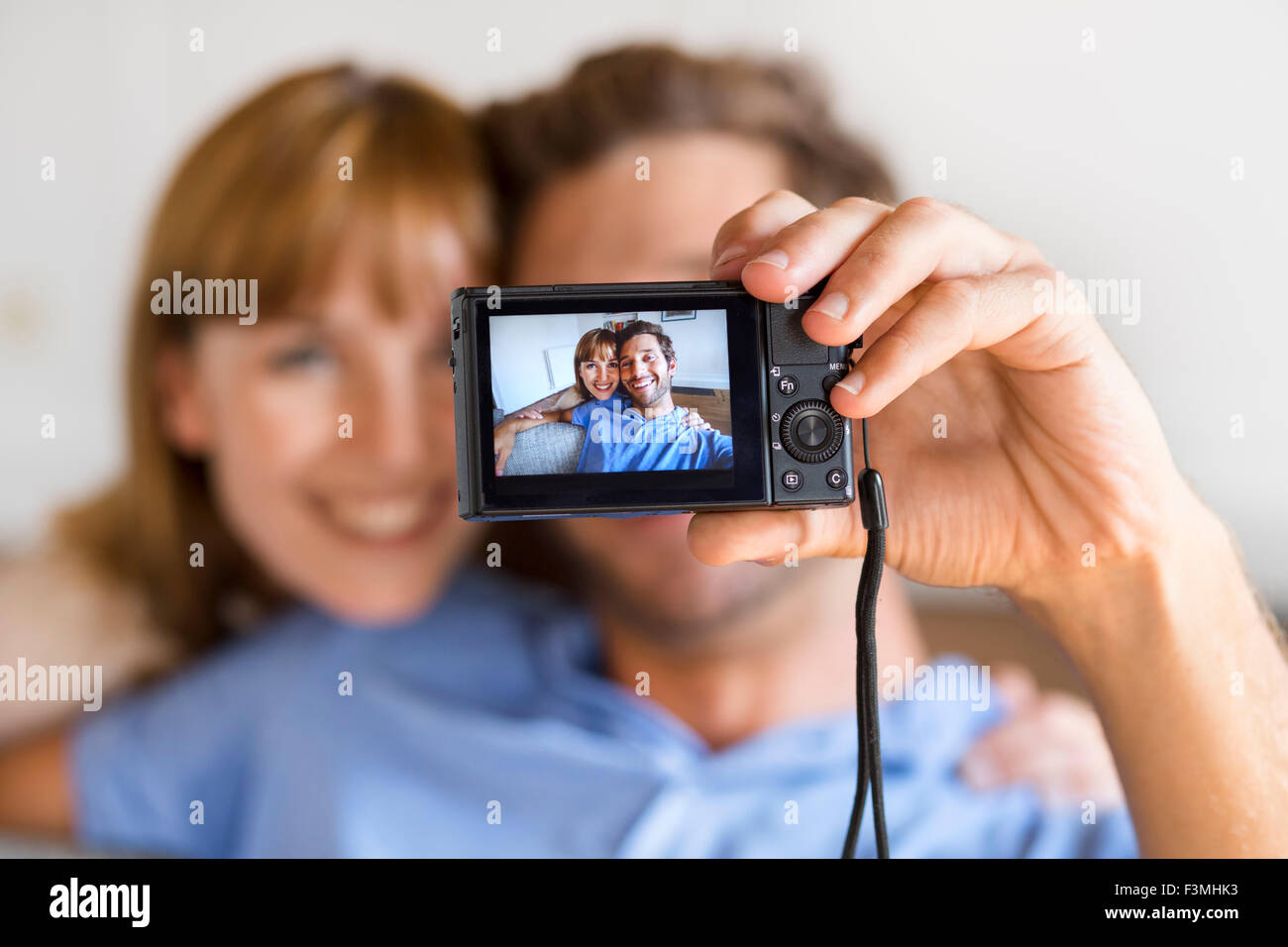 Allegro giovane prendendo un selfie con una telecamera. Casa bianca di sfondo Foto Stock