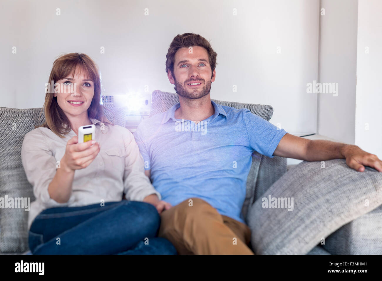 Paio di guardare un film con un video proiettore, sul divano confortevole Foto Stock