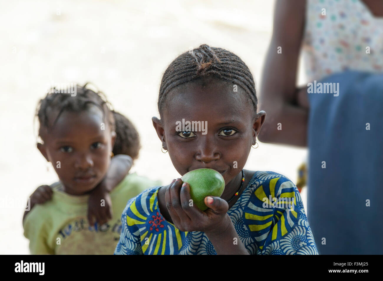 Unidentified bambino masticare green mango in Africa rurale Foto Stock