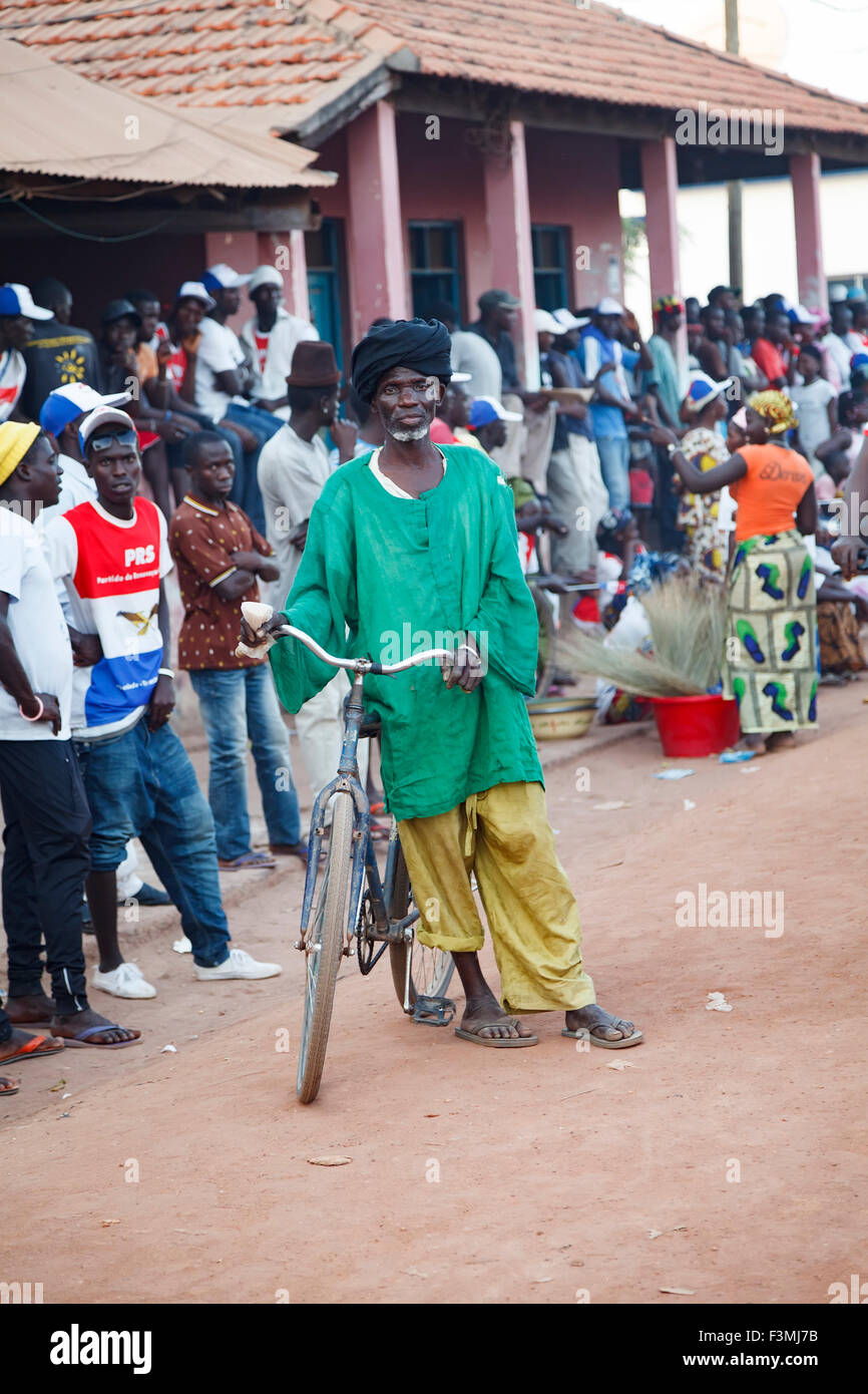 Ritratto di un uomo africano con la sua bicicletta in piedi in una folla di persone nelle zone rurali la Guinea Bissau Foto Stock