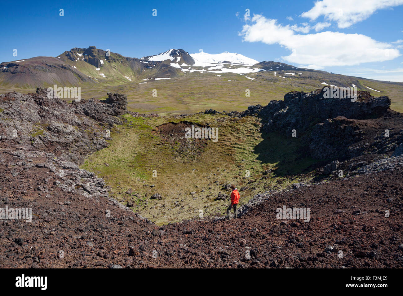 Persona sul bordo del cratere Saxholl, sotto Snaefellsjokull. Snaefellsjokull National Park, Snaefellsnes Peninsula, Vesturland, Islanda. Foto Stock