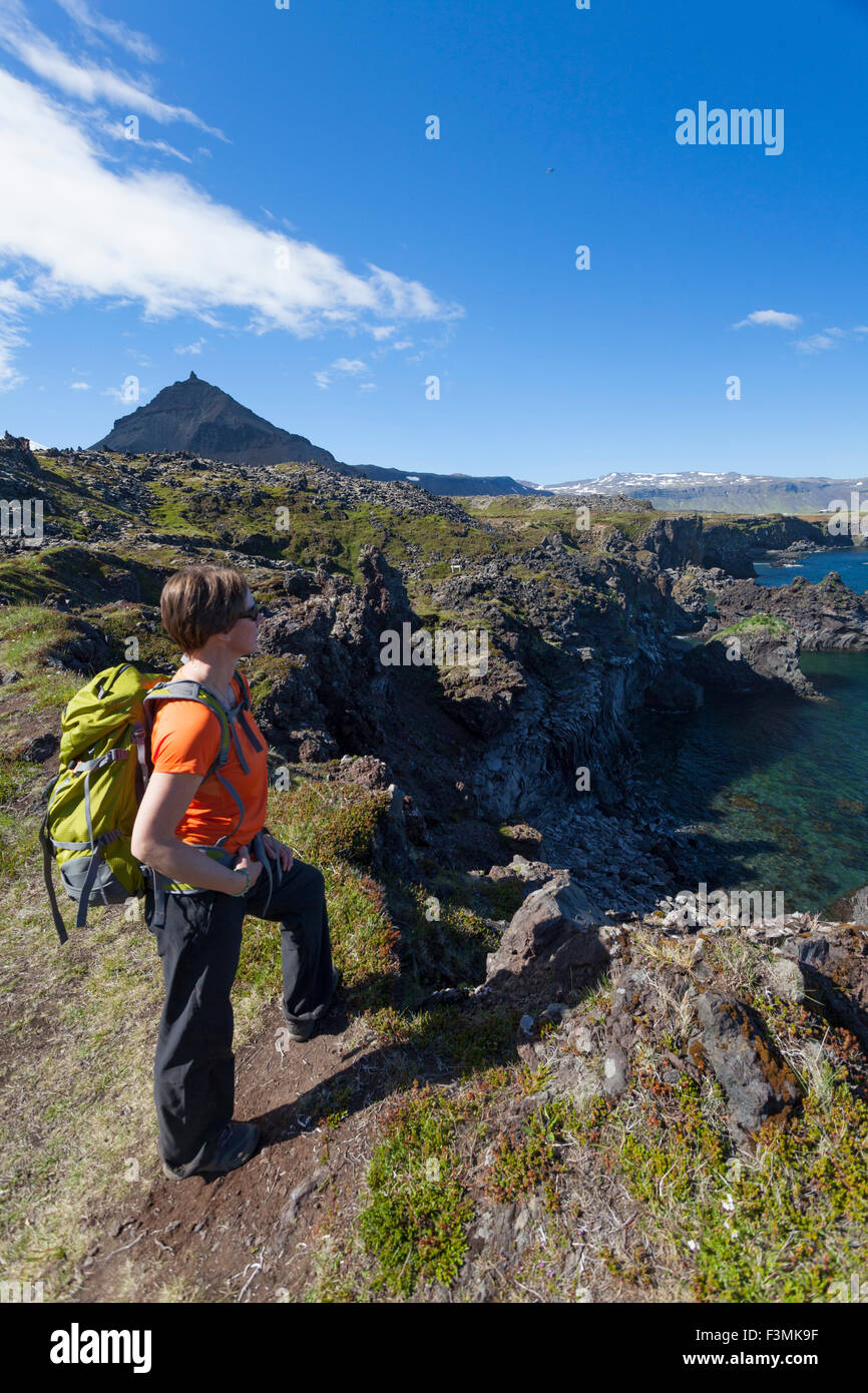 Escursionista sul Hellnar-Arnarstapi sentiero costiero, Snaefellsnes Peninsula, Vesturland, Islanda. Foto Stock