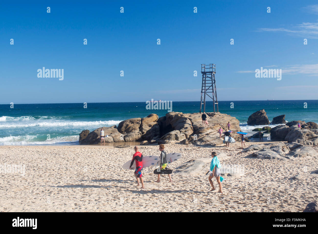 Redhead spiaggia con bagnino tower e surfers camminare tra la sabbia verso il mare Lago MAcquarie nei pressi di Newcastle New South Wales NSW Foto Stock