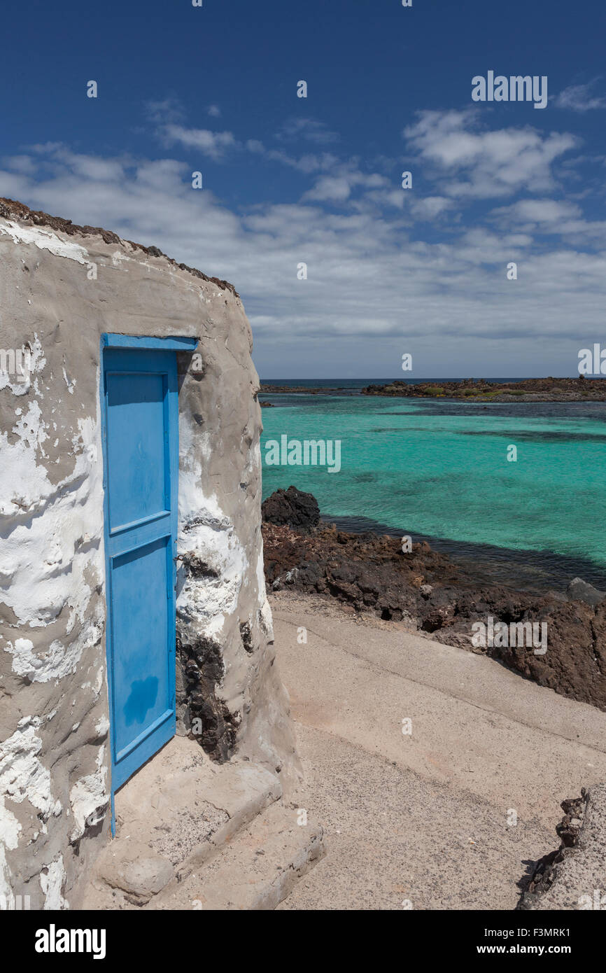 Porta blu di una vecchia casa con il mare azzurro in background Foto Stock