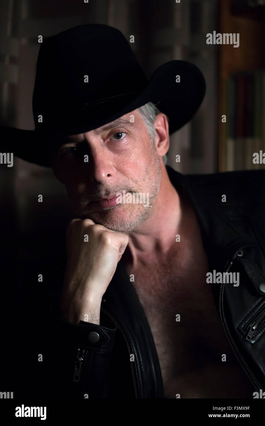 Uomo che indossa il cappello da cowboy, close up, illuminazione artificiale in ombra. Foto Stock