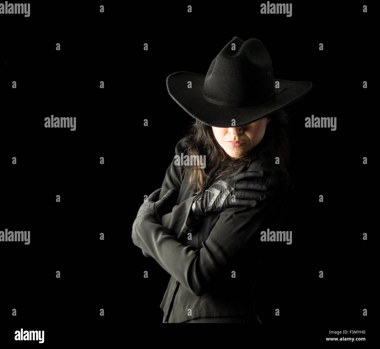 Brunette donna in abito nero e guanti neri, indossando un nero cappello da cowboy. Foto Stock