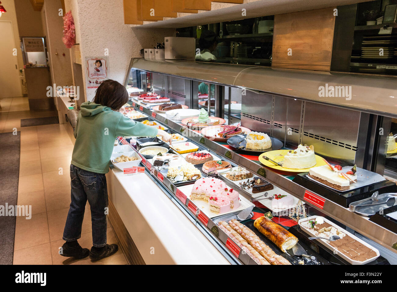 Giappone, Nishinomiya, 'Sweet Paradiso", interni di tutto quello che potete mangiare dolci e ristorante nel deserto. Ragazzo che serve se stesso dal contatore di dessert. Foto Stock