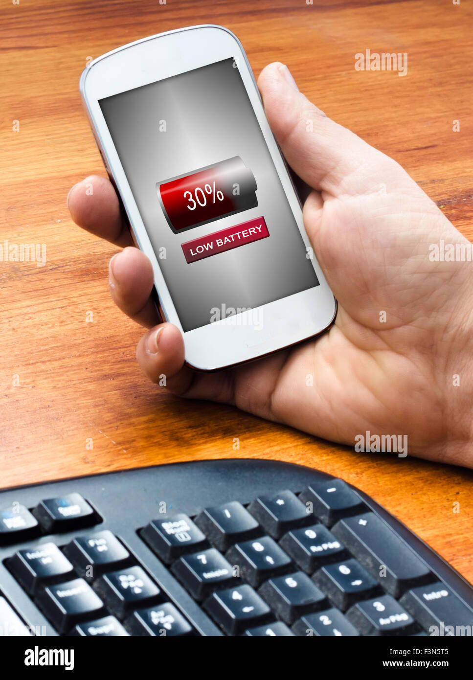 Un uomo con telefono cellulare sul tavolo con un basso l'icona della batteria nella schermata, soft focus Foto Stock