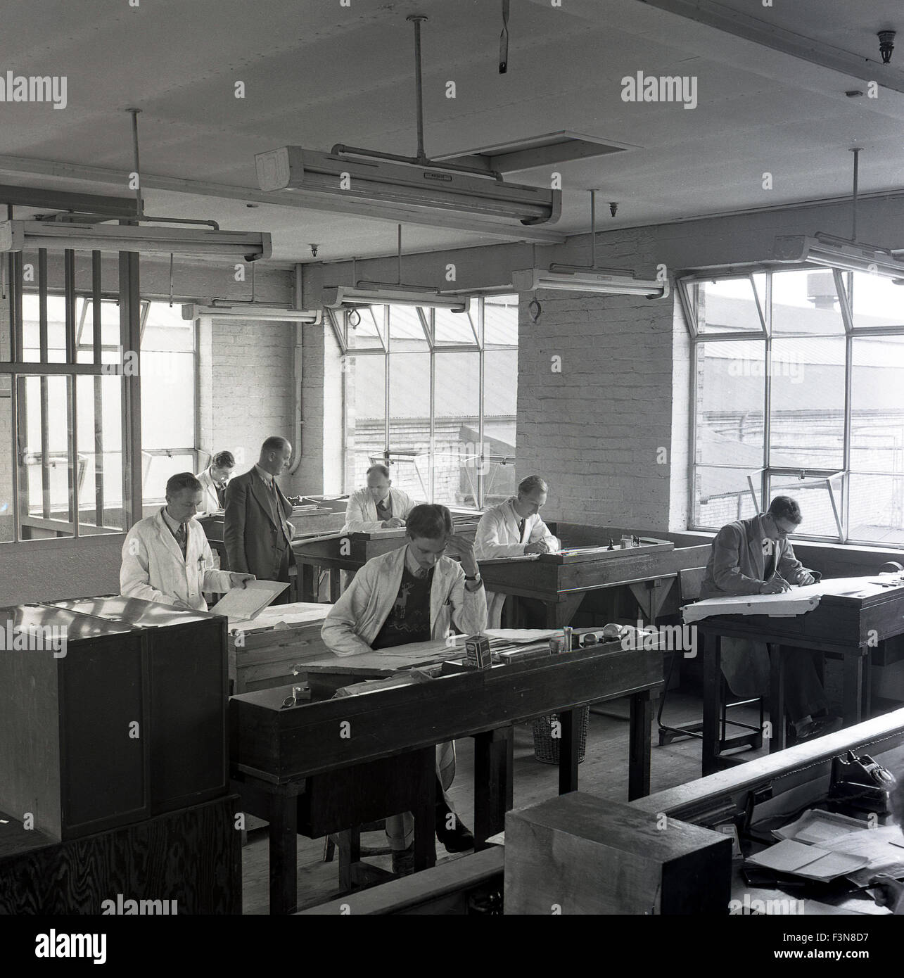 Anni '1950, storici, dipendenti maschi, alcuni in camici bianchi, che lavoravano presso scrivanie di legno nell'ufficio di progettazione e disegno della British Ever Ready Electrical Company a Dawley, Telford, Inghilterra, Regno Unito. Ever Ready era una grande azienda industriale britannica che produceva batterie, radio wireless e torce. Foto Stock