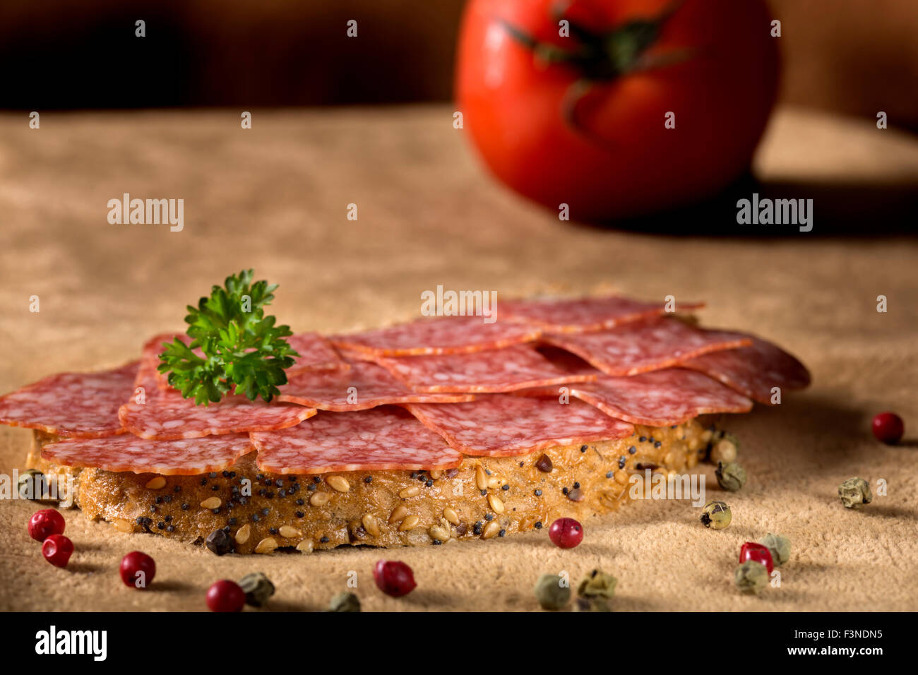 Foto di deliziosi salami sandwich con grani di pepe e prezzemolo Foto Stock