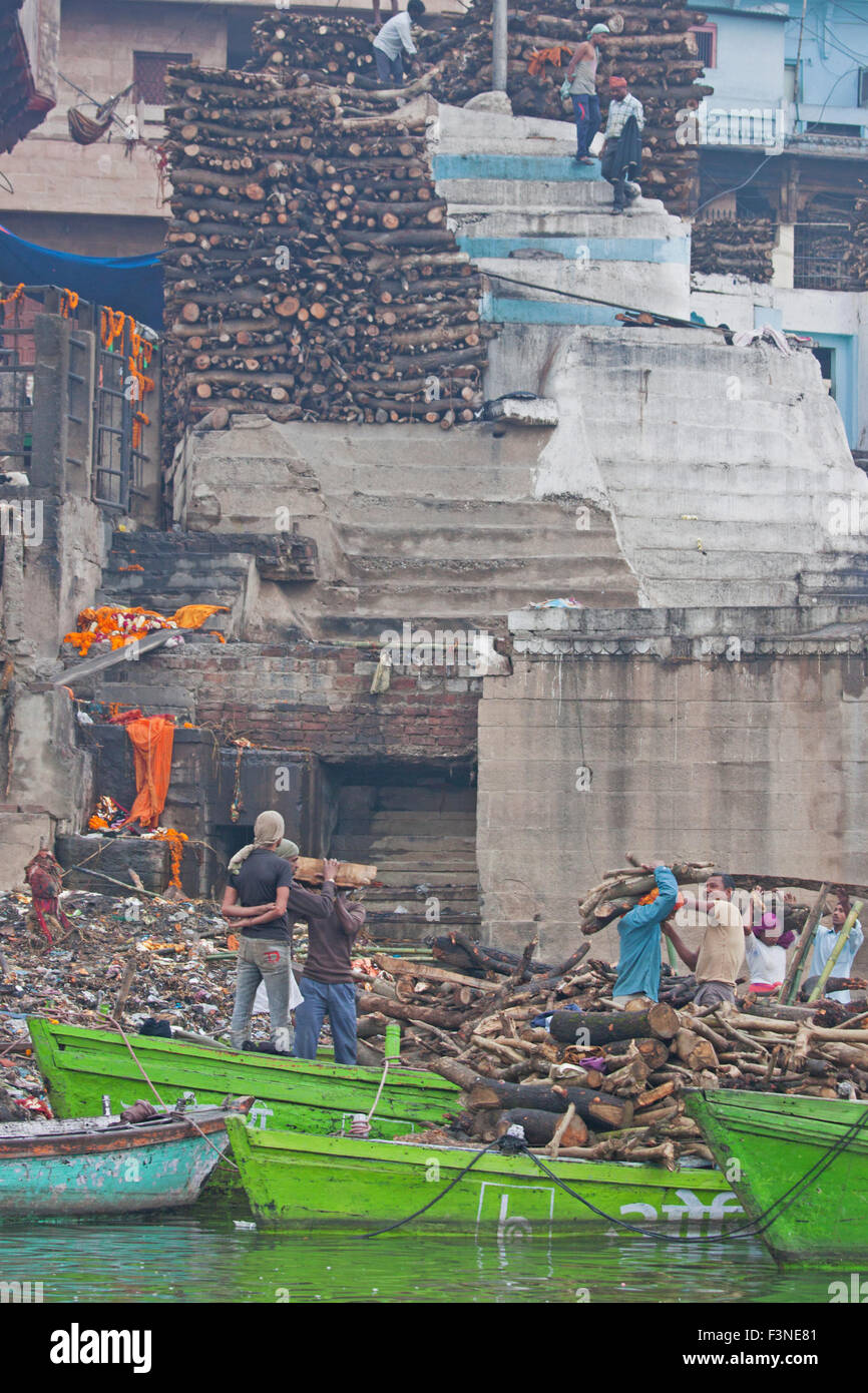 Il trasporto dei lavoratori legno per costruire roghi a Manikarnika ghat sul fiume Gange a Varanasi nelle prime ore del mattino Foto Stock