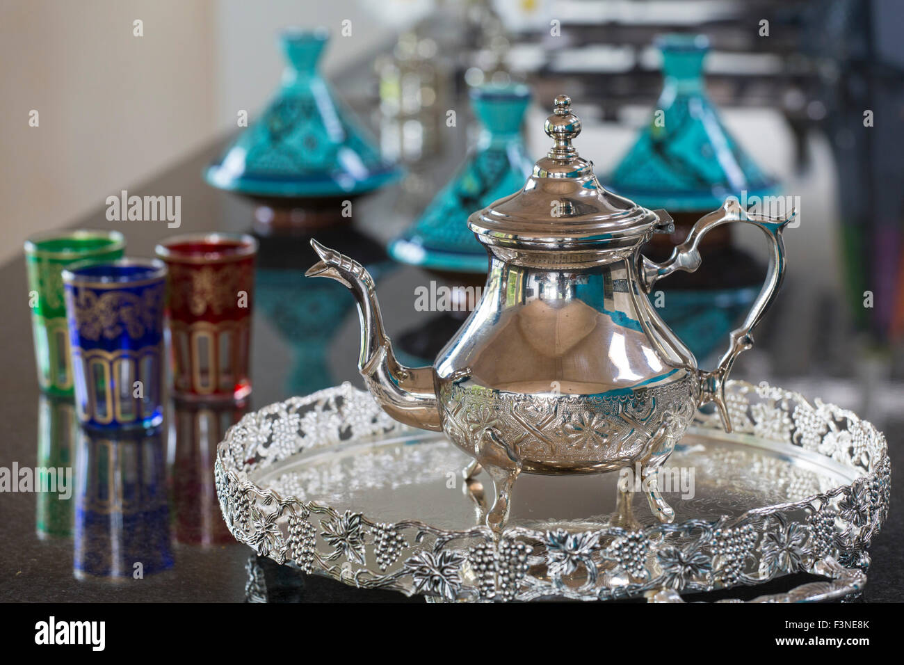 Teiera marocchino con gli occhiali e gli ingredienti di base di una tagine in background Foto Stock