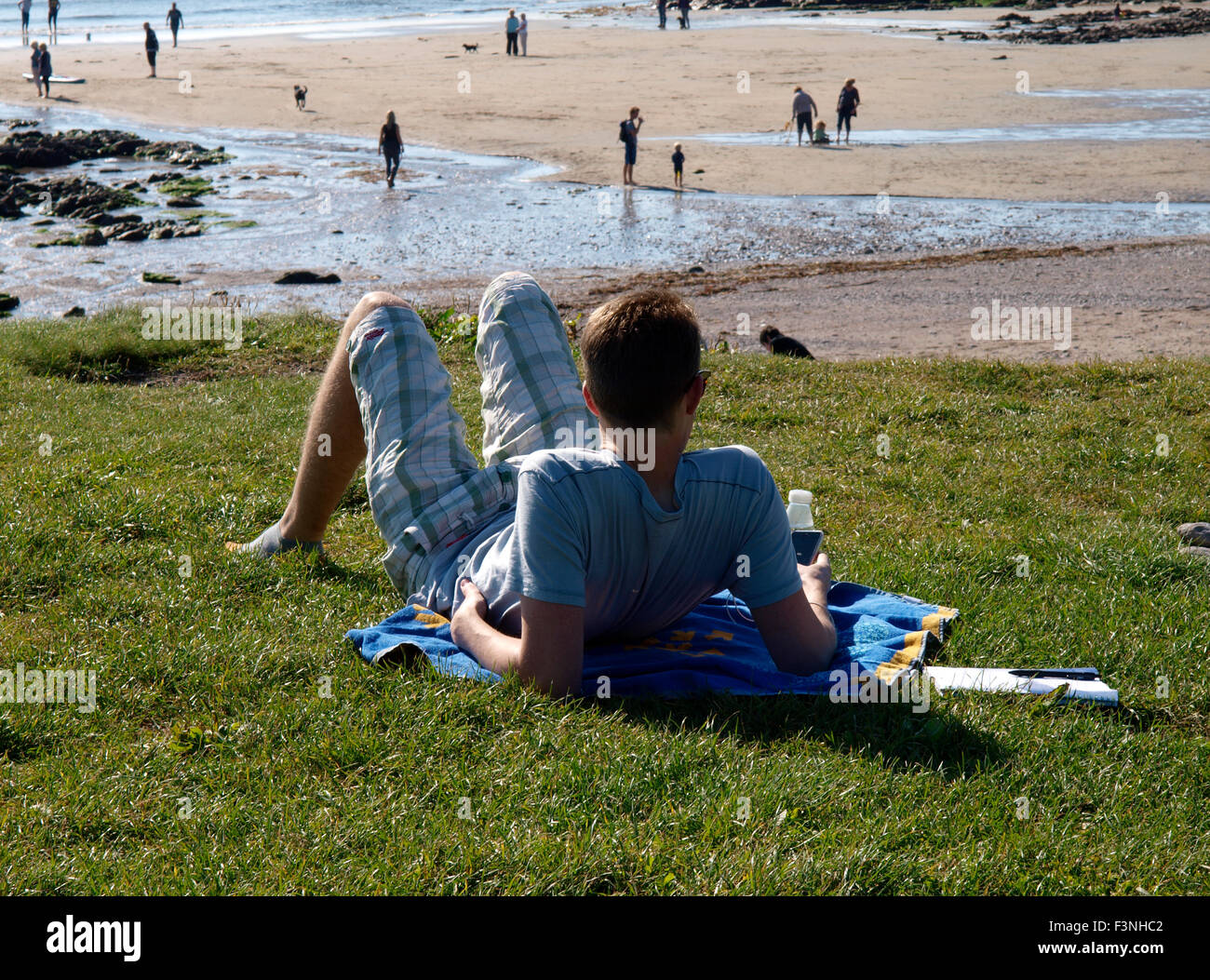 Giovani maschi adulti a rilassarci in spiaggia, Wembury, Devon, Regno Unito Foto Stock