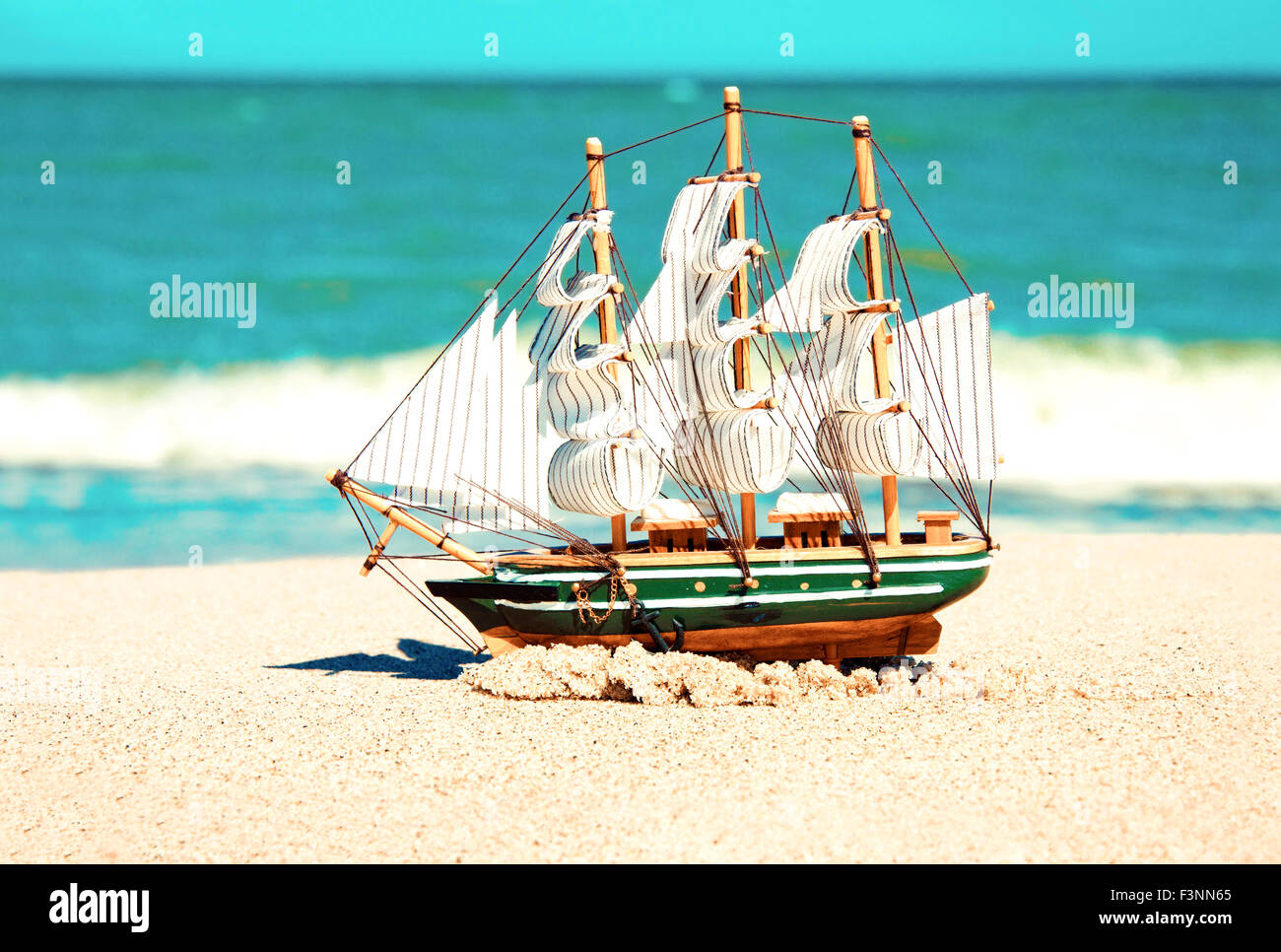 Souvenir immagine concettuale. Modello di nave in sabbia vicino all'oceano. Foto Stock