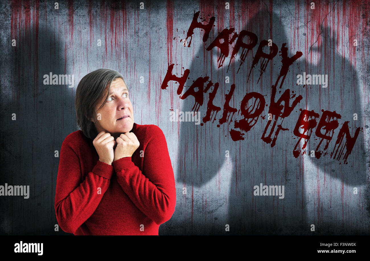 Happy halloween spruzzata su una sanguinosa parete accanto all'ombra di un fantasma e una paura donna Foto Stock