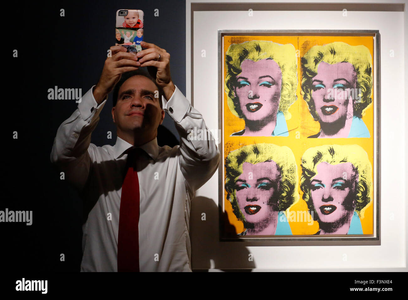 Francis Outred, presidente e capo di Post-War e arte contemporanea EMERI, pone con il suo telefono cellulare a fianco di artista Andy Warhol's artwork " Quattro Marilyns' alla casa d'aste Christie's di Londra, Regno Unito, Ottobre 9, 2015. È sul dispay nel Regno Unito durante il fregio decorato con Arte Fiera settimana fino al mese di ottobre 17 e sarà in vendita in 'Post-War e serata contemporanea Vendita di Christie's New York il 10 novembre. Stima disponibile su richiesta. Foto Stock