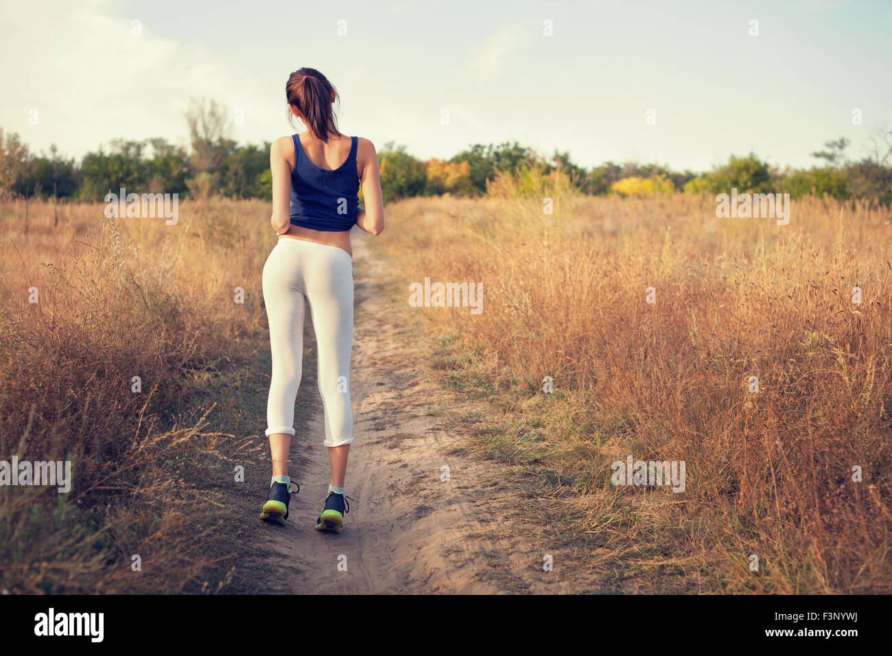 Giovane bella ragazza sport nella foresta di autunno al tramonto Foto Stock