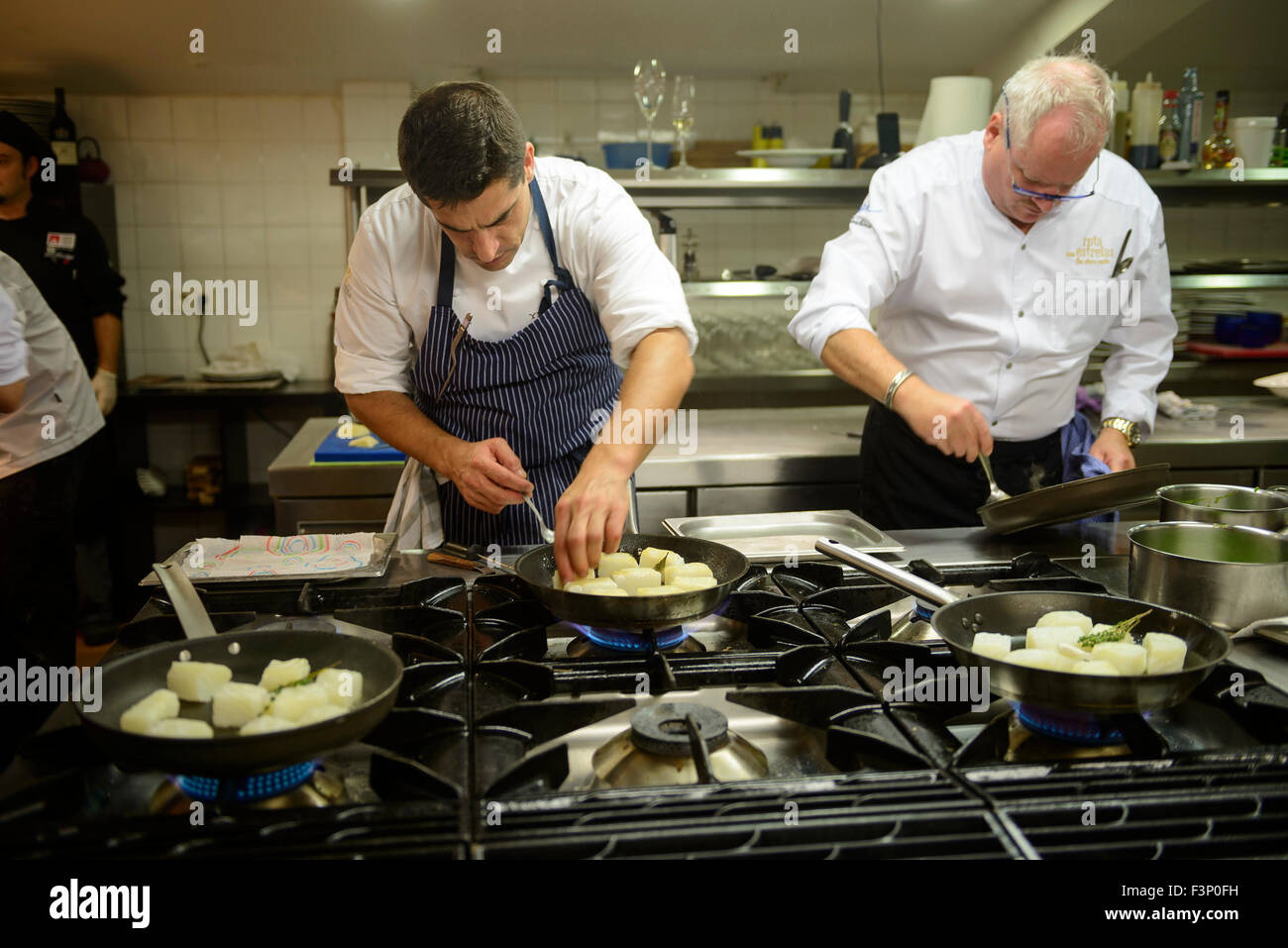 Lo chef portoghese Ricardo Costa e lo chef austriaco Dieter Koschina friggere il pesce su una cucina professionale Foto Stock