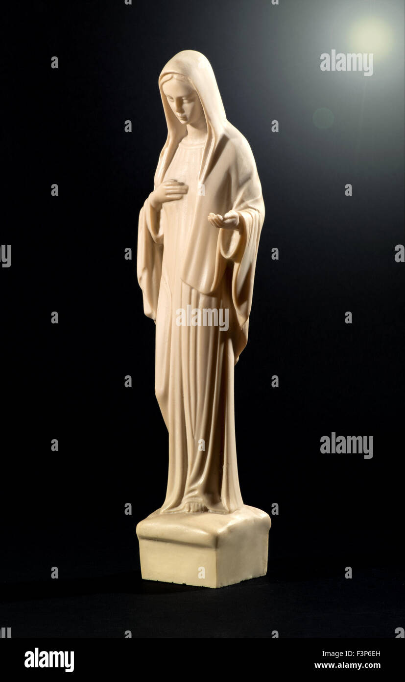 Pianura color crema figurale statua della Vergine Maria su sfondo nero Foto Stock