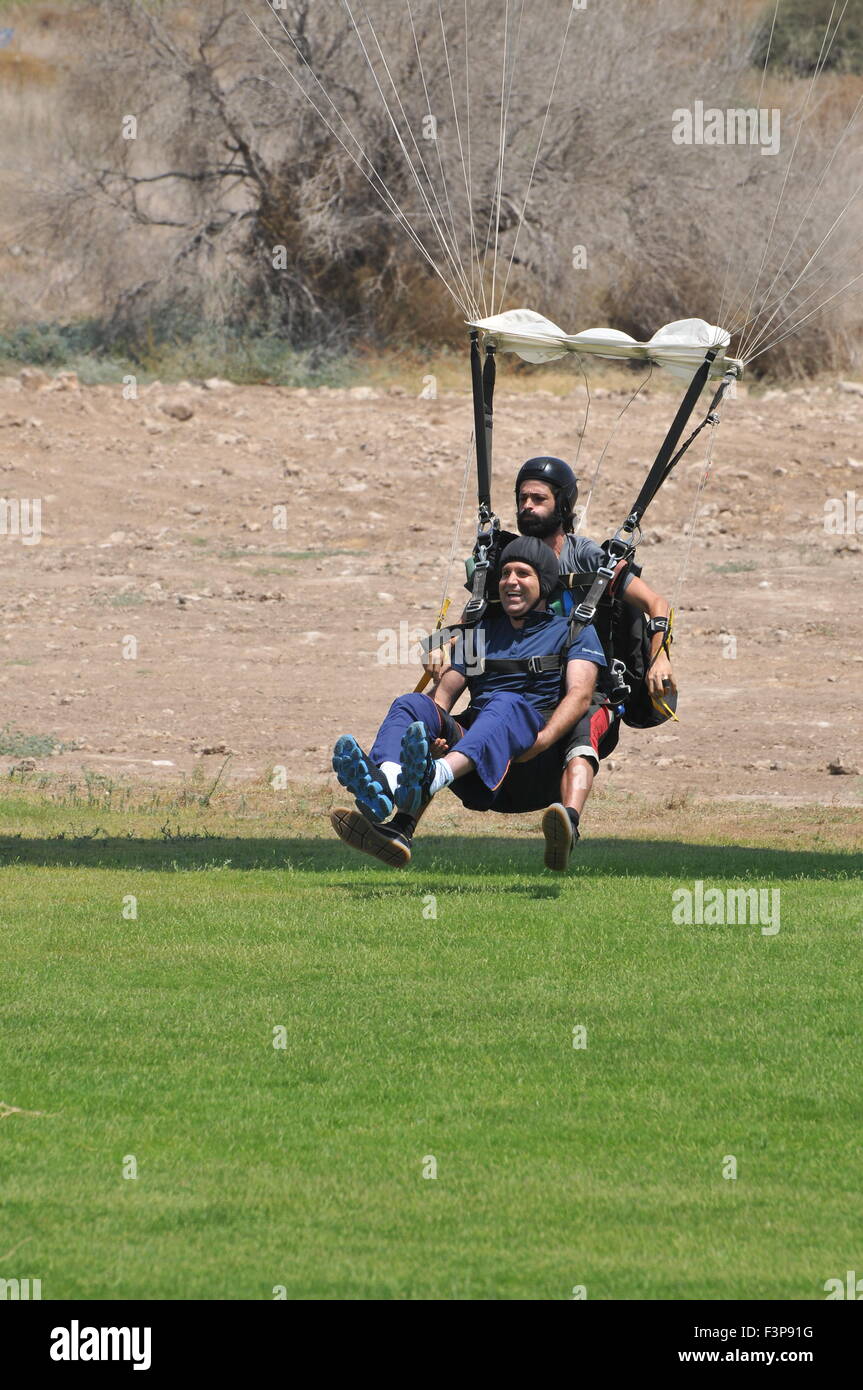 Il parapendio in tandem e istruttore partecipante legati insieme al momento dello sbarco Foto Stock