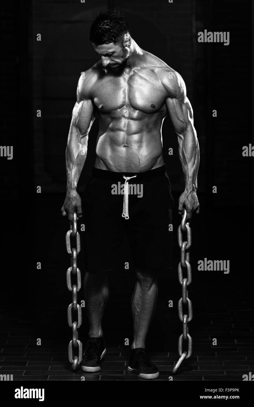 Ritratto di una adatta fisicamente l uomo che mostra il suo ben addestrato corpo e catene di contenimento Foto Stock
