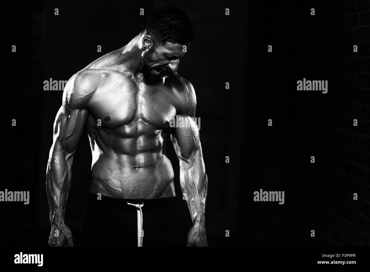 Ritratto di una adatta fisicamente l uomo che mostra il suo ben addestrato corpo e catene di contenimento Foto Stock
