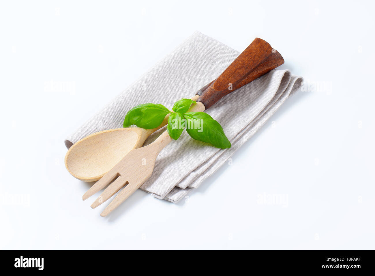 Forcella di legno e cucchiaio con basilico fresco sul tovagliolo Foto Stock