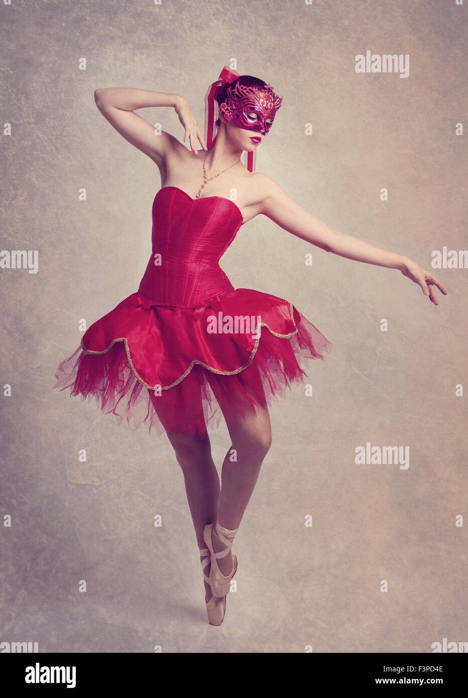 Un grazioso ballerina danza su point indossando un rosso tutu e una maschera rossa Foto Stock