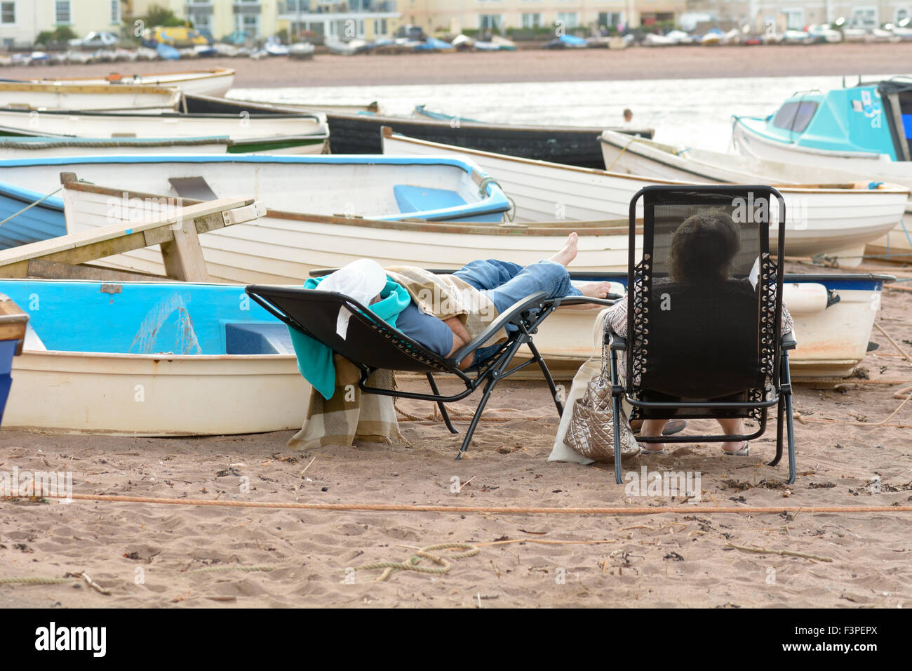 Due donne sdraiato sulle sedie a sdraio sulla spiaggia in una giornata di sole in Teignmouth, Devon, Inghilterra Foto Stock