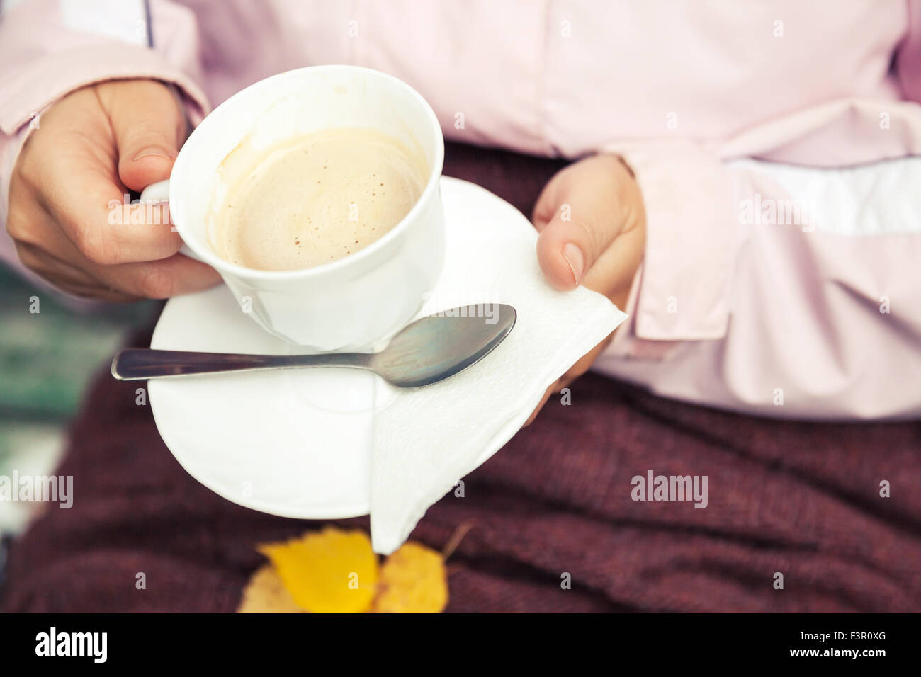 Tazza bianca piena di caffè con panna in mani femminili, foto all'aperto, parco di autunno Foto Stock