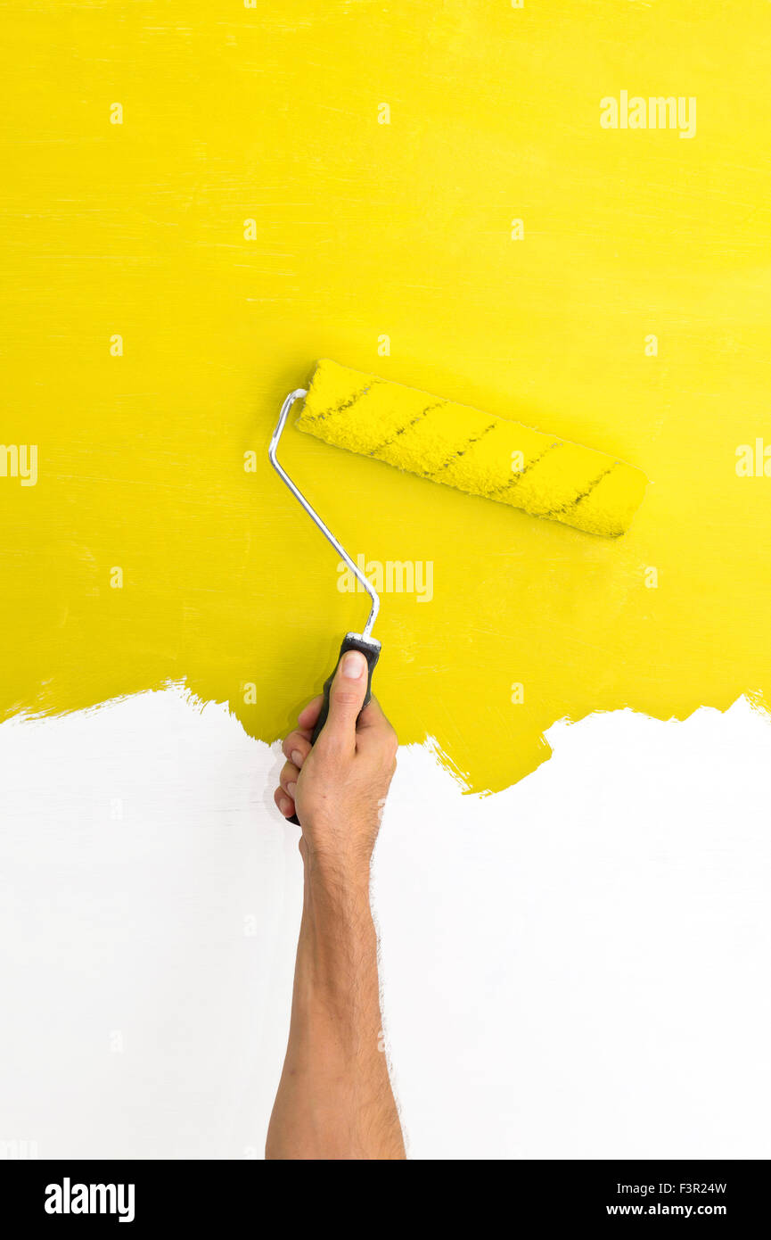 Pittura a parete utilizzando un rullo con vernice gialla Foto Stock