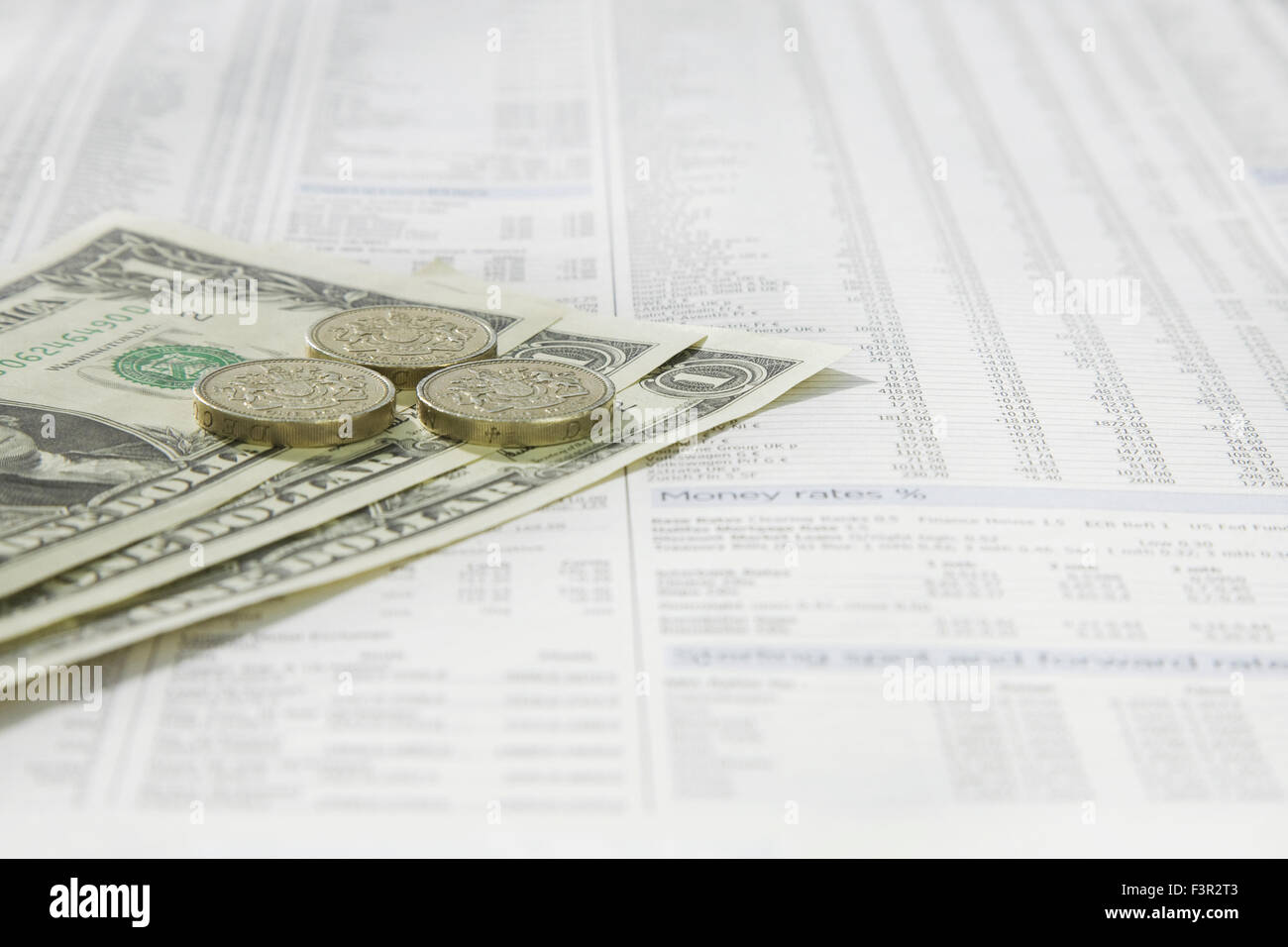 American un dollaro e British una libbra di monete su una carta di notizie del mercato azionario pagina finanziaria mostra titoli e azioni Foto Stock