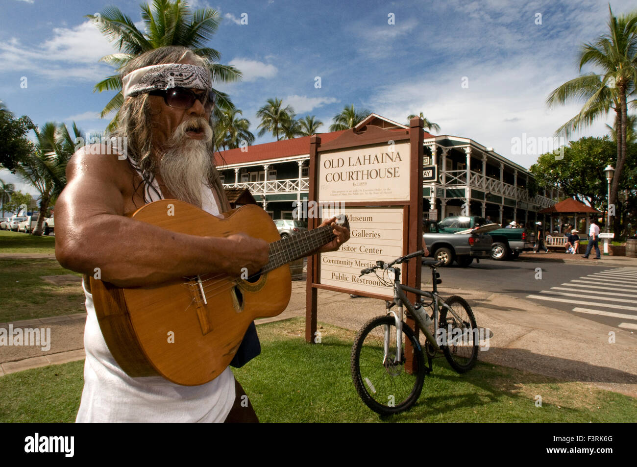 Hippye suonare la chitarra nei pressi del caratteristico e antico edificio giudiziario e penitenziario di Lahaina. Maui. Hawaii. Dalla sua apertura fanfa Foto Stock