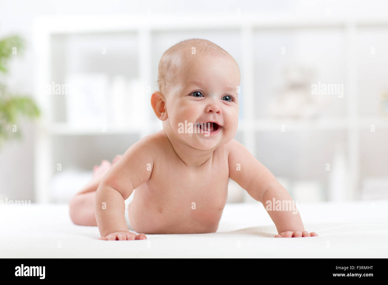 Felice piccolo Bimbo giacente sul ventre e sorridente Foto Stock