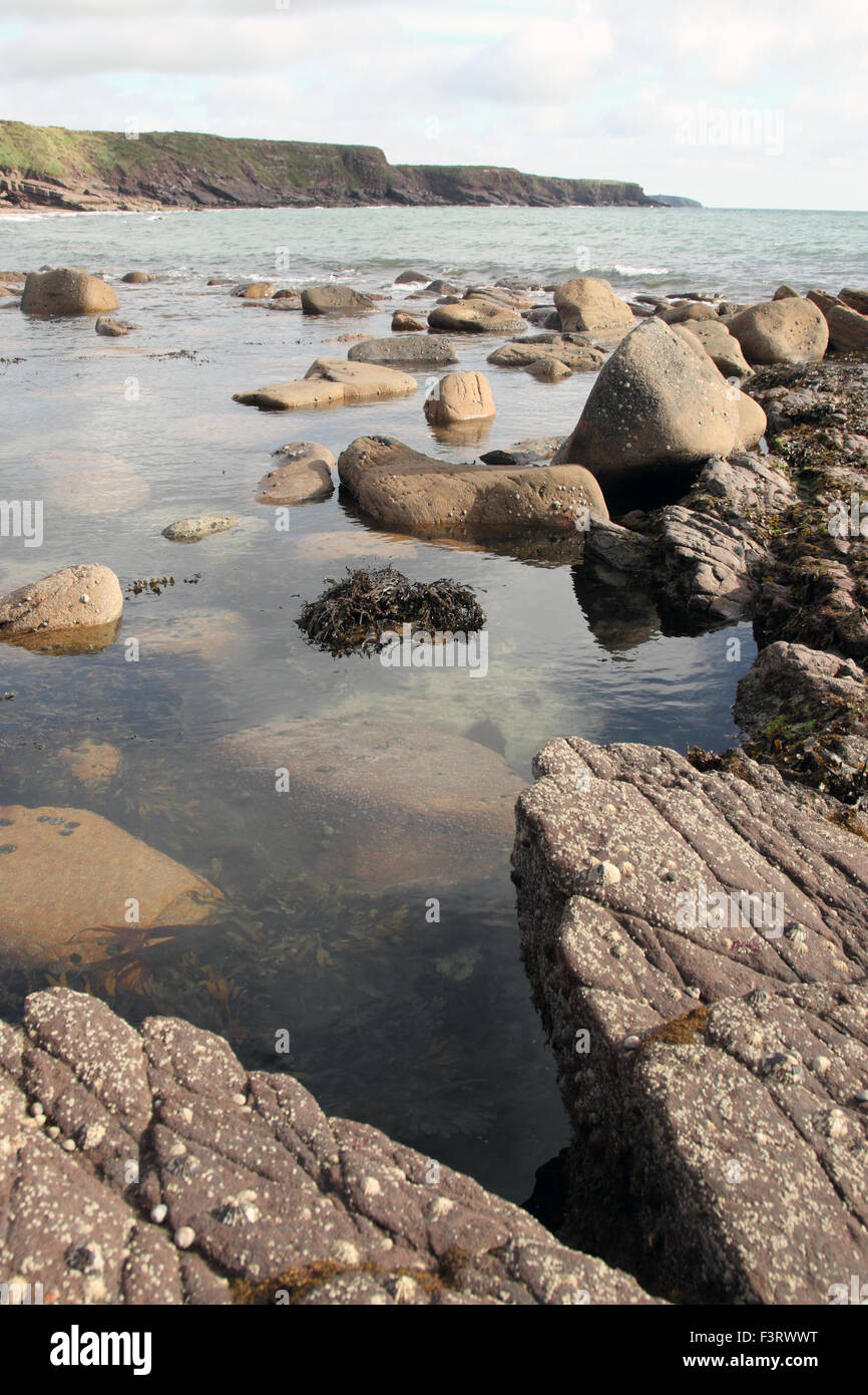 Marea di inghiottire un rock pool su una spiaggia rocciosa nel sud dell' Irlanda Foto Stock