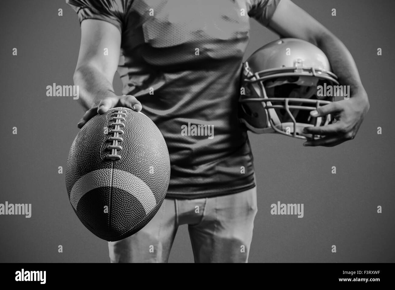 Immagine composita della sezione intermedia di uno sportivo che mostra il football americano tenendo casco Foto Stock